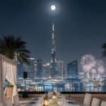 A luxury rooftop Iftar setup in Dubai featuring a white dining tent, glowing lanterns, and a view of the Burj Khalifa under a full moon with fireworks.