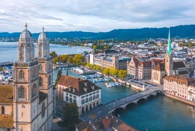 Aerial view of Zurich skyline featuring Grossmünster towers, Limmat River, and Lake Zurich in Switzerland.